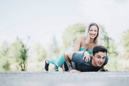 Active friends enjoying outdoor exercise in park with playful piggyback workout session and joyful...