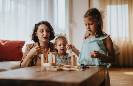 Mother and daughters playing with blocks at home togetherの写真素材