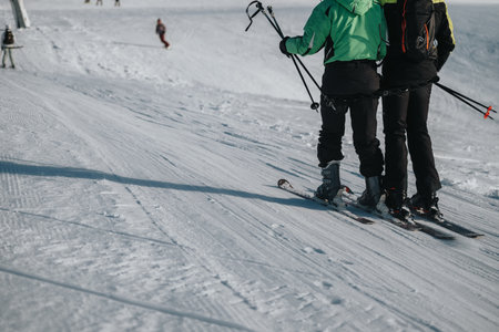 Two people skiing together on a snowy slope in a winter landscapeの写真素材