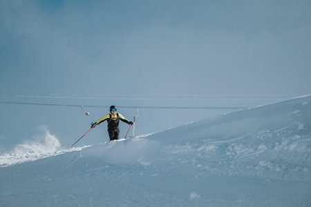 Person skiing downhill on a snowy slope under a bright clear skyの写真素材