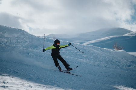 Skier in bright gear on snowy mountain slopeの写真素材