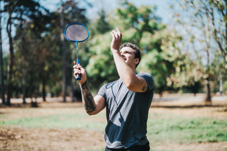 Young man playing badminton in a sunny park settingの写真素材