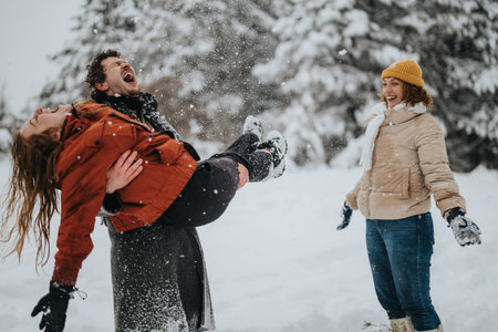 Group of friends enjoying the winter season with playful laughter amidst snowy outdoor sceneryの写真素材