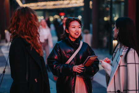 Group of Friends Conversing Outdoors at Night in Urban Settingの写真素材