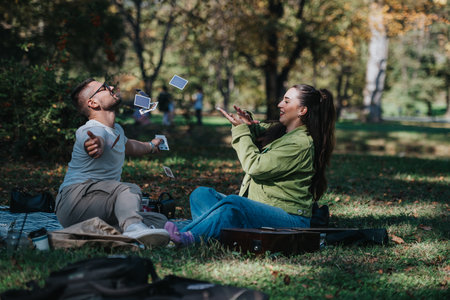 Young couple enjoying card magic trick in a sunny autumn parkの写真素材