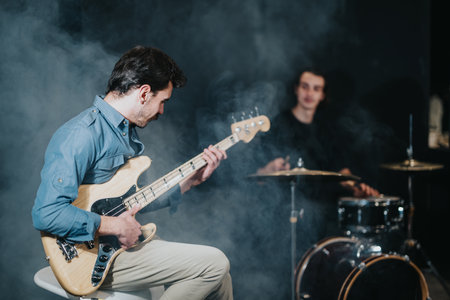 Musicians rehearsing together with guitar and drums in a smoky atmosphereの写真素材