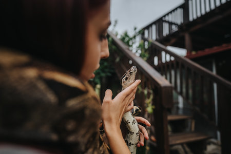 Girl holding a snake on wooden stairs in outdoor settingの写真素材