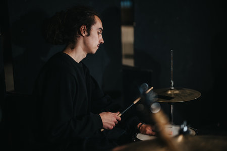 Young musician playing drums in an intimate and dimly lit performance spaceの写真素材