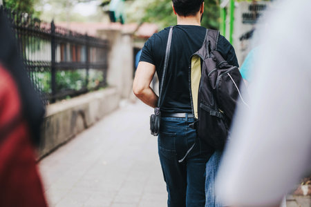 Man with backpack walking down a city sidewalk outdoors