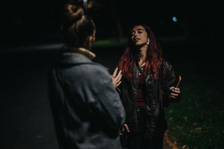 Two Women Conversing Outdoors at Night for a Dramatic Sceneの写真素材