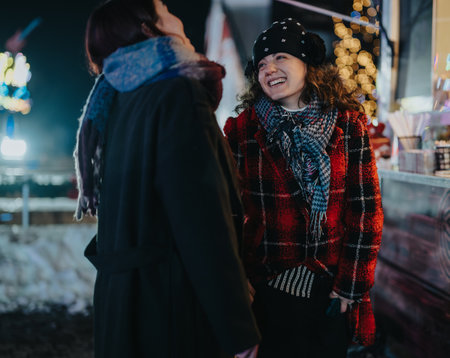 Two friends laughing and enjoying winter holiday festivities outdoorsの写真素材