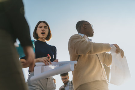 Business people discussing outdoor project plans on a sunny dayの写真素材