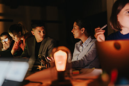 Group of business people working together late at night, discussing ideas in a dimly lit office...
