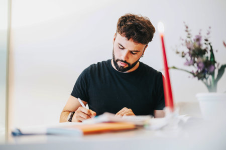 Focused college student studying at home with candlelight and flowersの写真素材