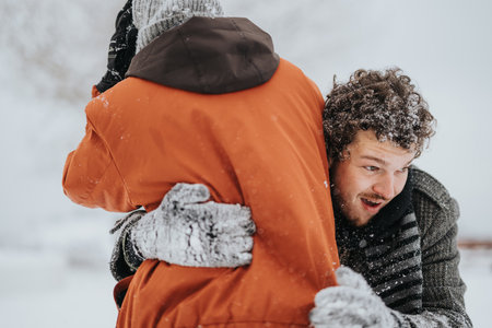 Two Friends Embracing in a Snowy Winter Outdoor Settingの写真素材