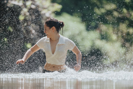 Happy woman enjoying splashing water in a sunny outdoor settingの写真素材