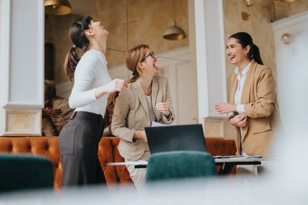 Businesswomen Laughing and Collaborating in a Stylish Office Settingの写真素材