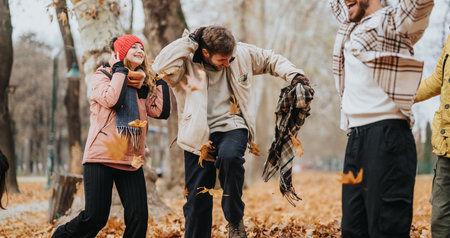 Group of friends enjoying autumn in a park, playing and laughing among colorful fallen leaves