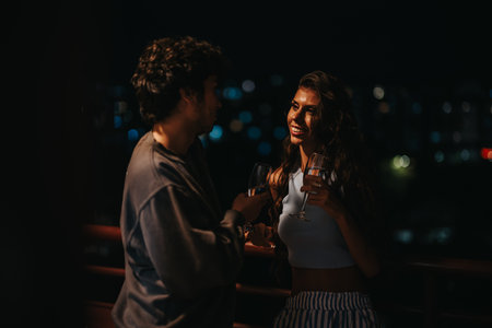 Couple enjoying a romantic evening on a rooftop with wine glassesの写真素材