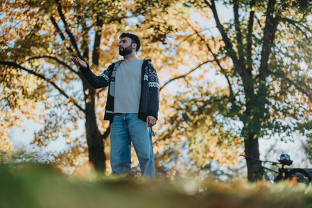 Man standing in autumn park enjoying nature with bicycle nearbyの写真素材