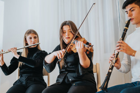 Three musicians playing violin, flute, and clarinet in an indoor settingの写真素材