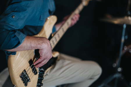 A close-up view of a bass guitarist playing during a band rehearsal, showcasing musical skill and...