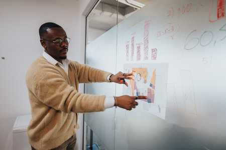 Multicultural business worker analyzing data on glass boardの写真素材