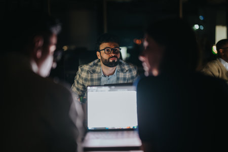Business coworkers collaborating late at night in dimly lit office spaceの写真素材