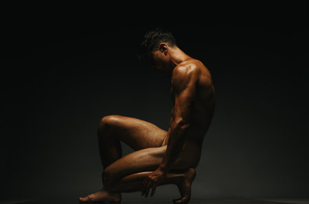 Artistic nude figure in dim studio lighting creating a serene atmosphereの写真素材