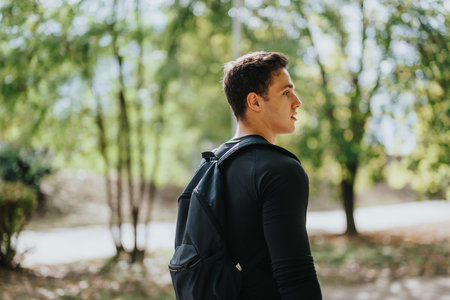 Young adult enjoying an outdoor walk through nature while carrying a backpackの写真素材