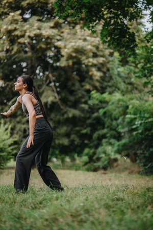 Young woman practicing mindful movement in a lush green parkの写真素材