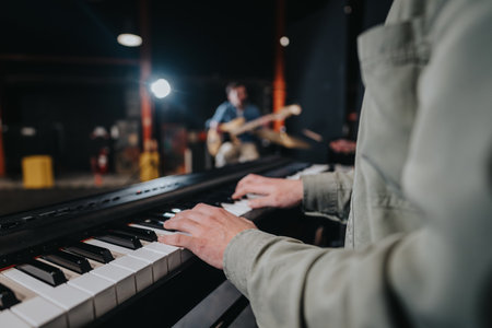 Musician playing keyboard during a lively band rehearsal performance at night