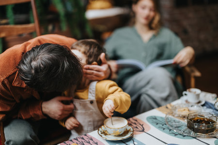 Father shares a tender moment with his child as mother reads in a cozy home interiorの写真素材