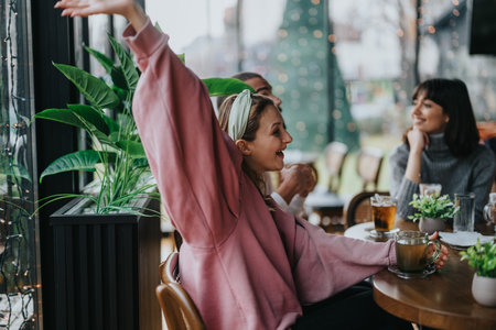 Friends enjoying time at a cozy cafe with warm drinks and laughter.の写真素材