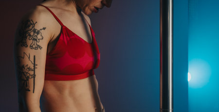 Woman features in a dimly lit pole fitness studio with bright colored lightsの写真素材