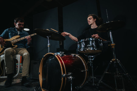 Musicians rehearsing with bass guitar and drums in a dimly lit studio