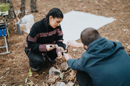 Two Friends Starting a Campfire During a Winter Outdoor Picnicの写真素材
