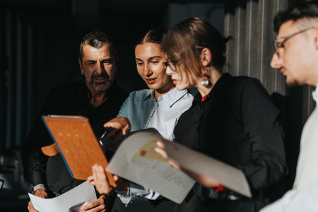 A diverse group of business people collaborates over documents in an office.の写真素材