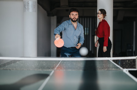 Multicultural business workers enjoying a ping pong game during breakの写真素材