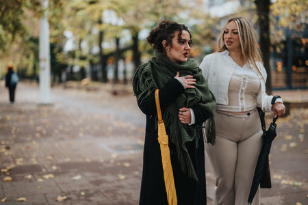 Two friends walking outdoors conversing in an autumn park settingの写真素材