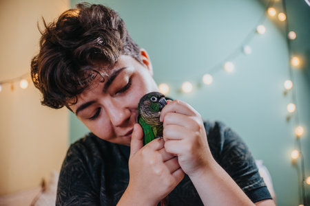 Girl gently cuddles parrot in cozy home settingの写真素材