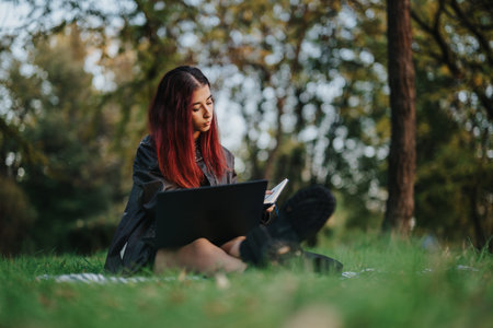 Young woman reading with laptop in peaceful forest settingの写真素材