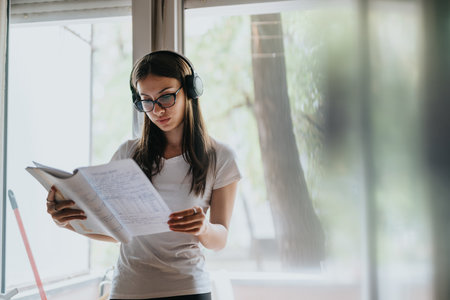 Focused young woman studying with headphones and notebookの写真素材