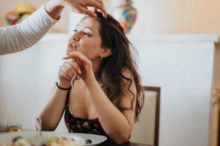 Woman enjoying playful moment at dining table with friendの写真素材