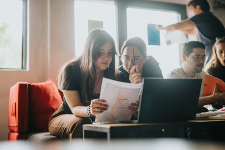 Students collaborating on school assignments with technology and documentsの写真素材