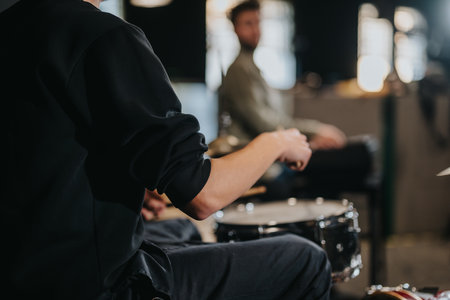 A close-up view of a drummer practicing during a group band rehearsal, displaying artistic concentration and musical creativity in a studio setting.の写真素材