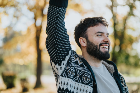 Joyful man in a sweater smiling broadly in a sunny autumn parkの写真素材