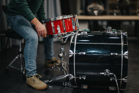 Drummer setting up drum kit in a studio rehearsal spaceの写真素材