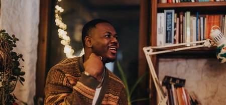 Man smiling while enjoying a cozy ambiance filled with books and soft light