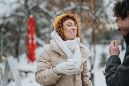Friends enjoying warm drinks outdoors on a snowy winter dayの写真素材